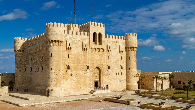 A grand stone fortress under a blue sky with clouds.
