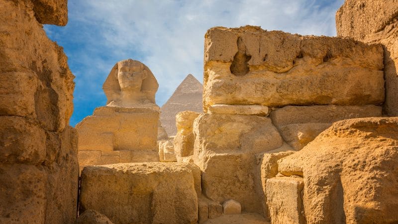 Travelers walking through a historic Egyptian site with ancient columns and intricate carvings