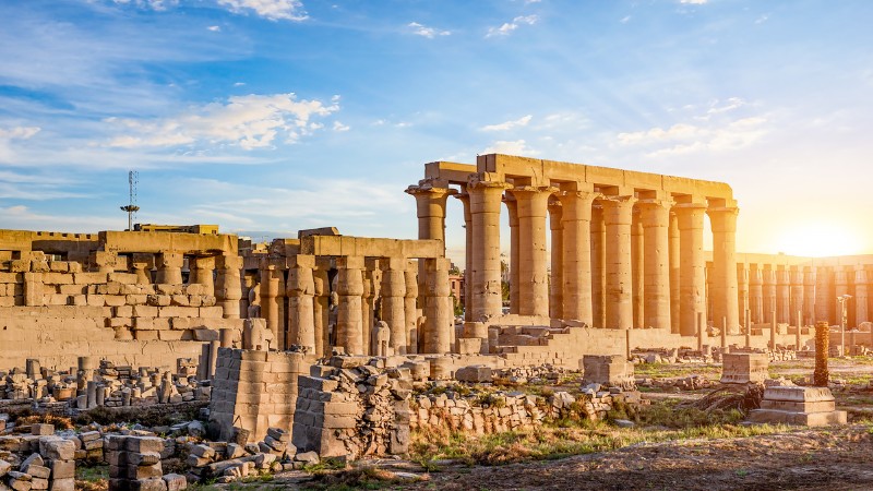"Ruins of Luxor Temple with the sun rising behind."