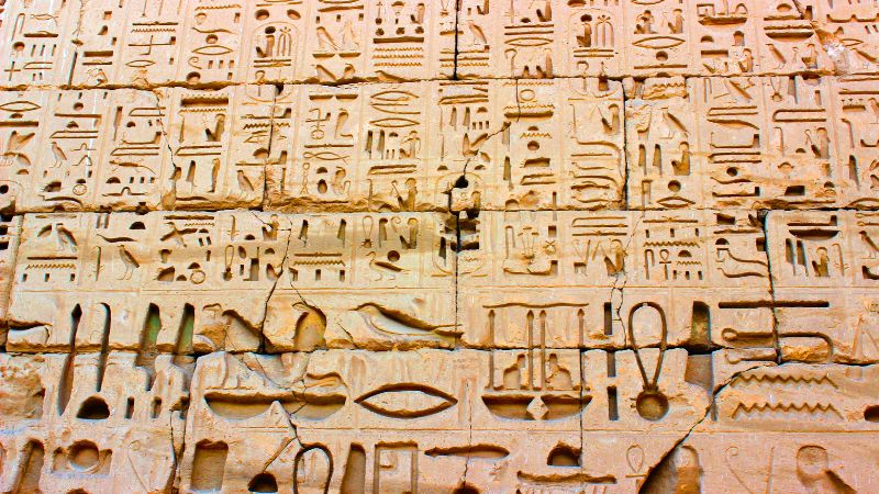 Close-up of hieroglyphic inscriptions on an ancient sandstone wall, showcasing intricate carvings and symbols