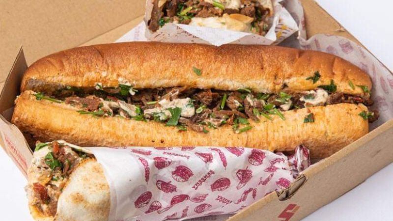 A box of freshly prepared shawarma sandwiches, stuffed with meat, herbs, and sauce