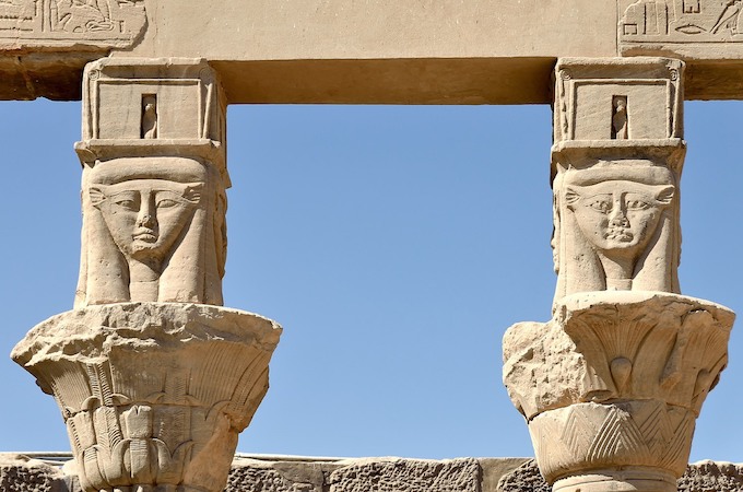 Carved stone columns of Isis Temple under a clear sky in Aswan.