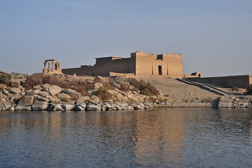 A traditional felucca sailing boat passing by the Kalabsha temple on the Nile River.