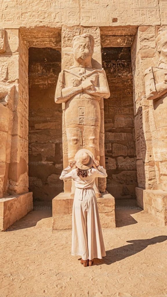 A breathtaking view of Luxor Temple in Egypt, illuminated at night with its towering columns and ancient statues reflecting in a tranquil water body