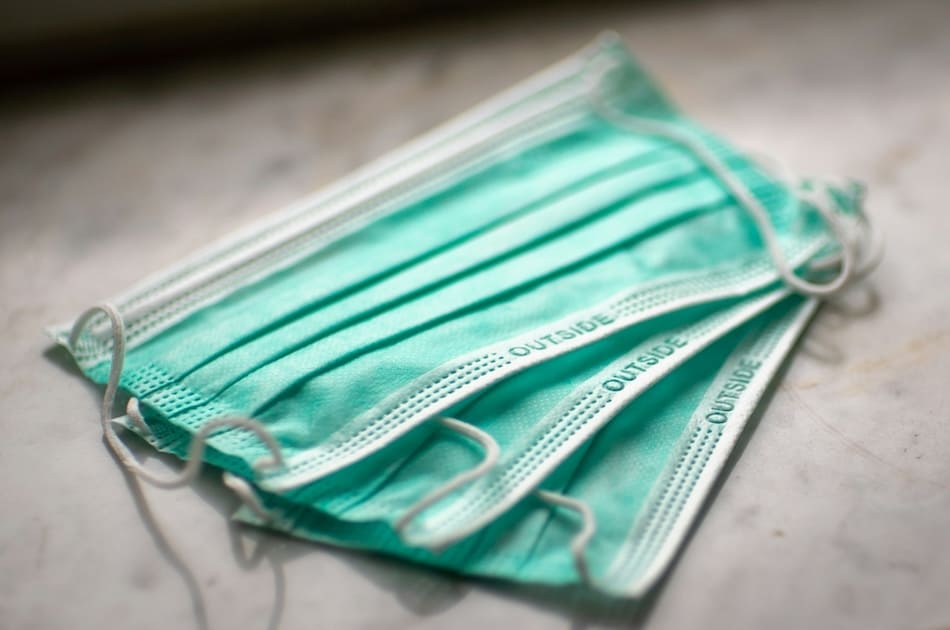 Three teal masks with the word "OUTSIDE" printed on them, indicating the proper orientation for wear.