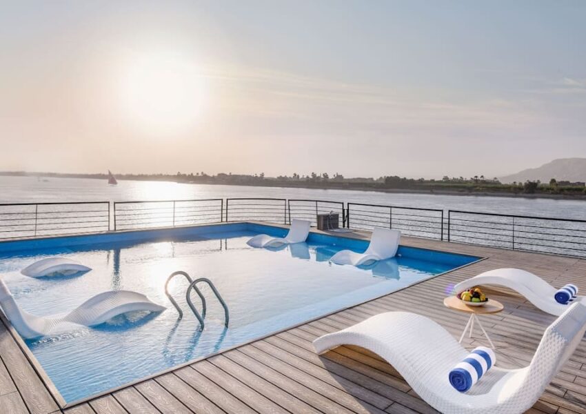 Infinity pool on a sundeck overlooking a river at sunset.