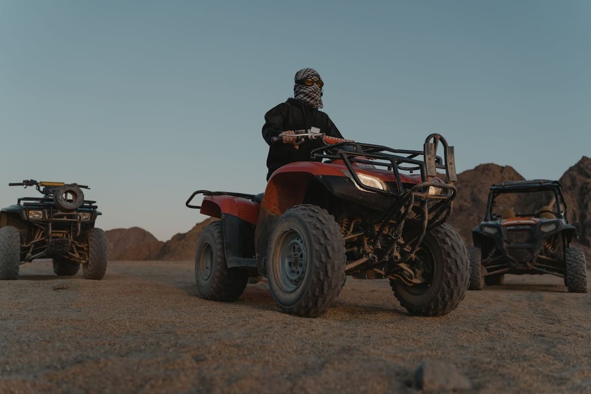 A thrilling scene of a person riding a quad bike across sandy dunes near Sharm El Sheikh, under a clear blue sky.