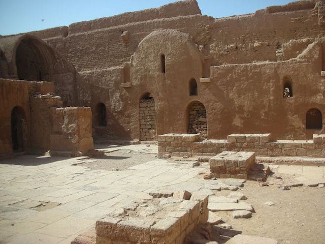 The ancient sandstone walls of Saint Simeon Monastery under a clear sky.