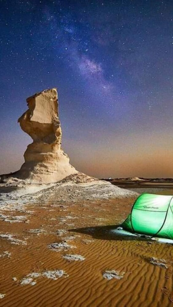 Green tent pitched under a rock formation in Egypt’s White Desert at night