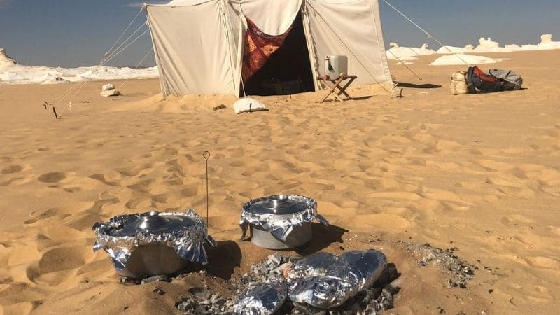 A camping tent with a fire pit in Egypt’s White Desert surrounded by surreal landscapes