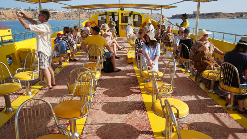 Tourists on the open deck of a sightseeing boat enjoying a coastal tour.