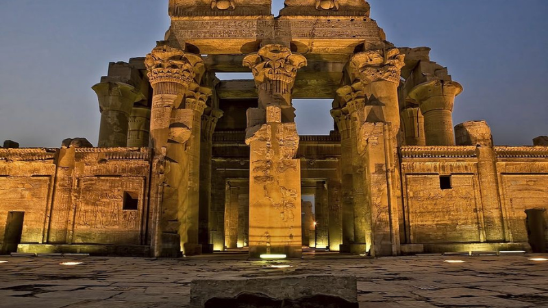 Illuminated night view of Kom Ombo temple's columned corridor.