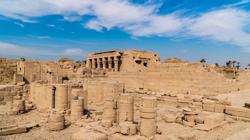 Ruins of an Egyptian temple with columns and scattered stone blocks.